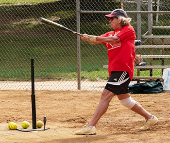 Woman hitting softball off the tee.