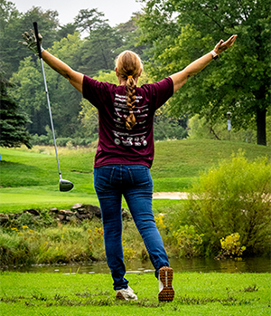 Woman holding golf club celebrating her shot.