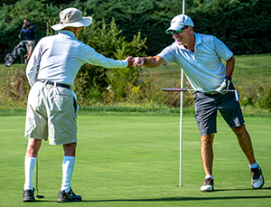 Men cheering on each other following a golf shot.