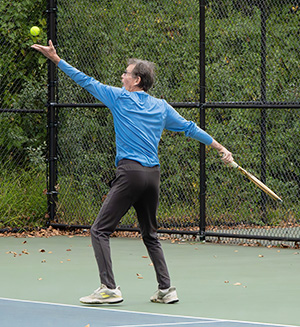 Man serves tennis ball.