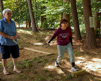 Two women playing horseshoes.